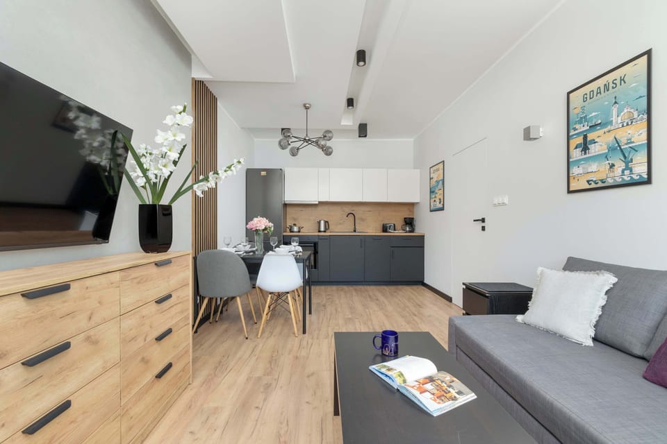 A contemporary living room with a gray L-shaped sofa and black coffee table. Stylish posters on the wall add a pop of color.