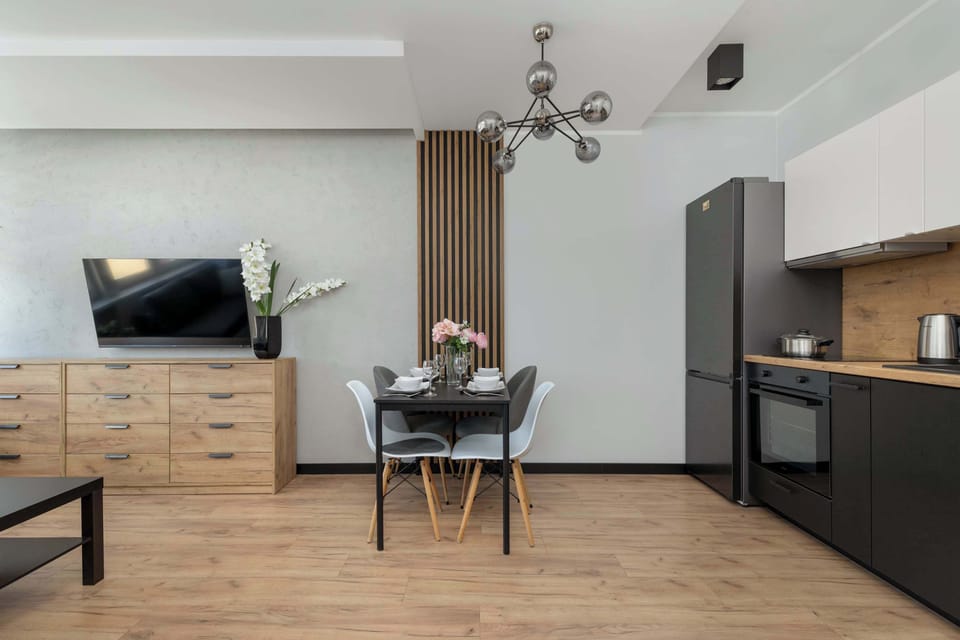 A spacious open-plan living room with a dining table and TV. The neutral tones create a calming atmosphere.