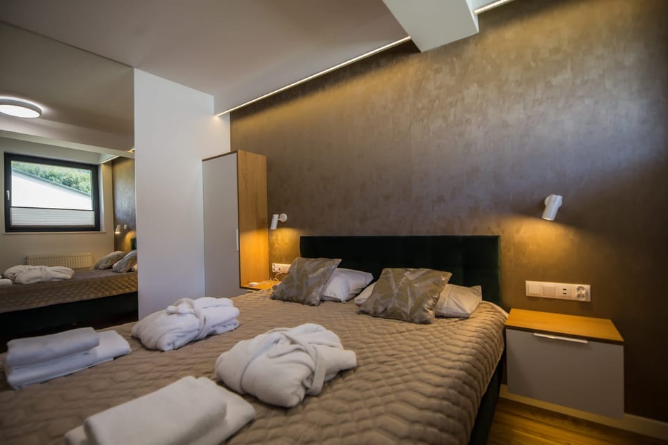 Another view of the bedroom with large bed, gray tones, and bedside lamps.