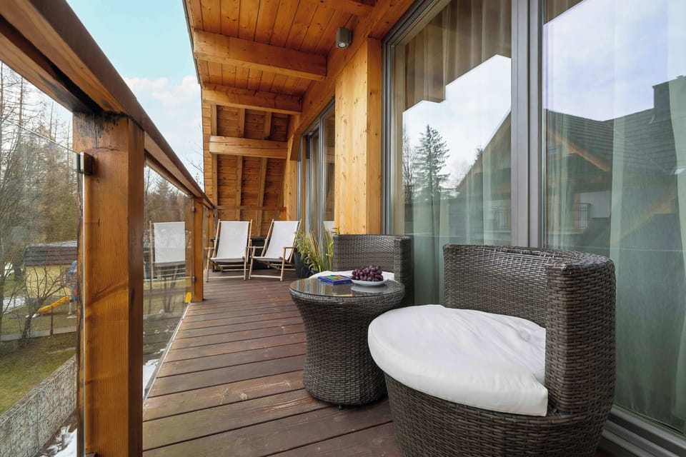 A wide view of the balcony area with outdoor seating, glass railing, and mountain landscape in the distance.

