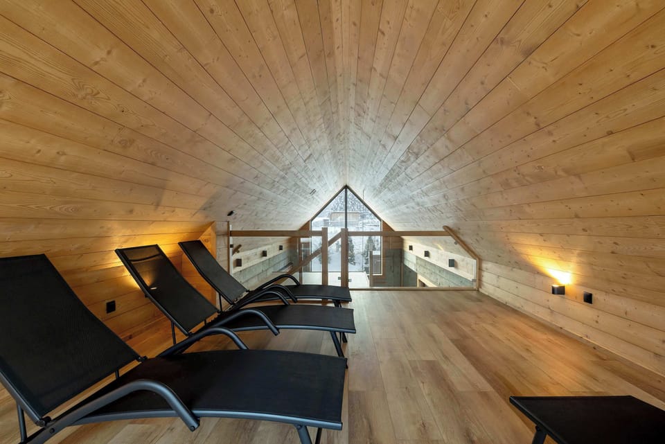 A close-up of a room with a wooden ceiling and comfortable lounge chairs under warm lighting.