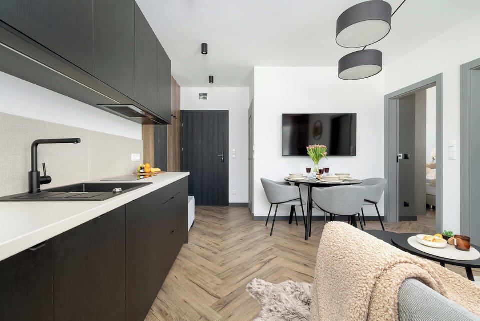 A kitchen with modern black cabinetry and a small dining table set for two.