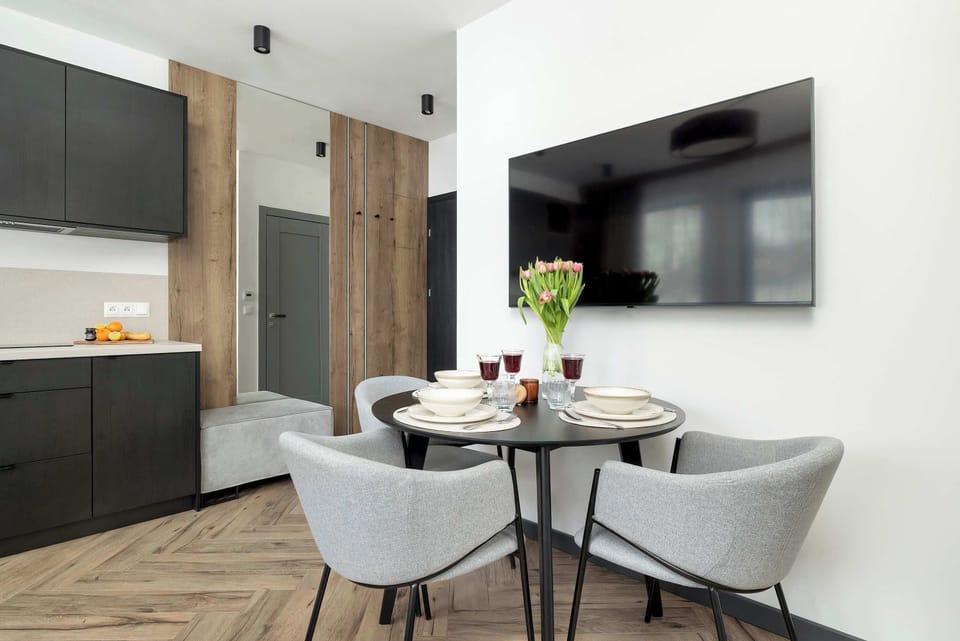 A dining table placed near a modern kitchen with clean black-and-white finishes.