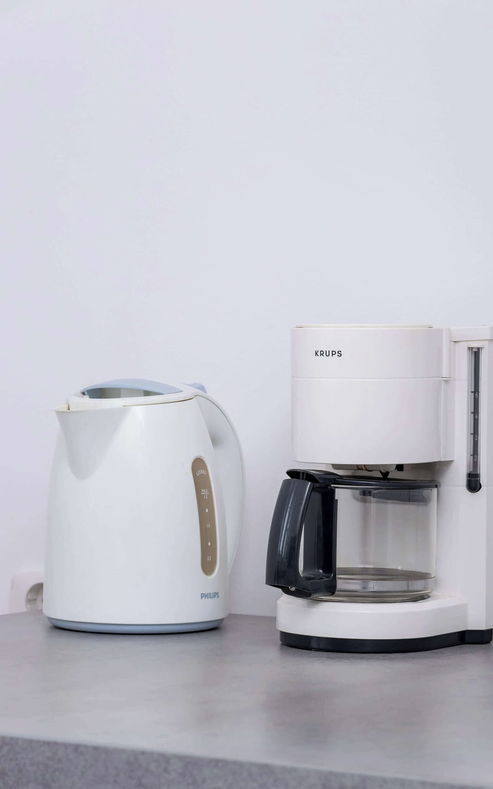 A coffee station with a white kettle and a coffee maker placed on a countertop. The compact setup is perfect for morning routines.