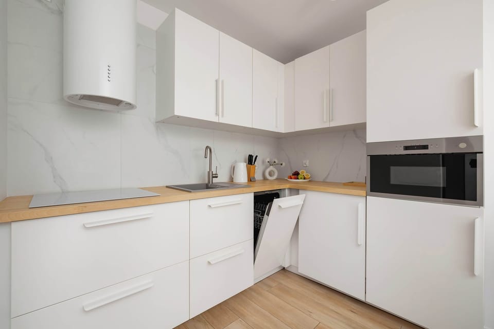 Modern kitchen area – Fully equipped white kitchen with built-in appliances and minimalist design.

