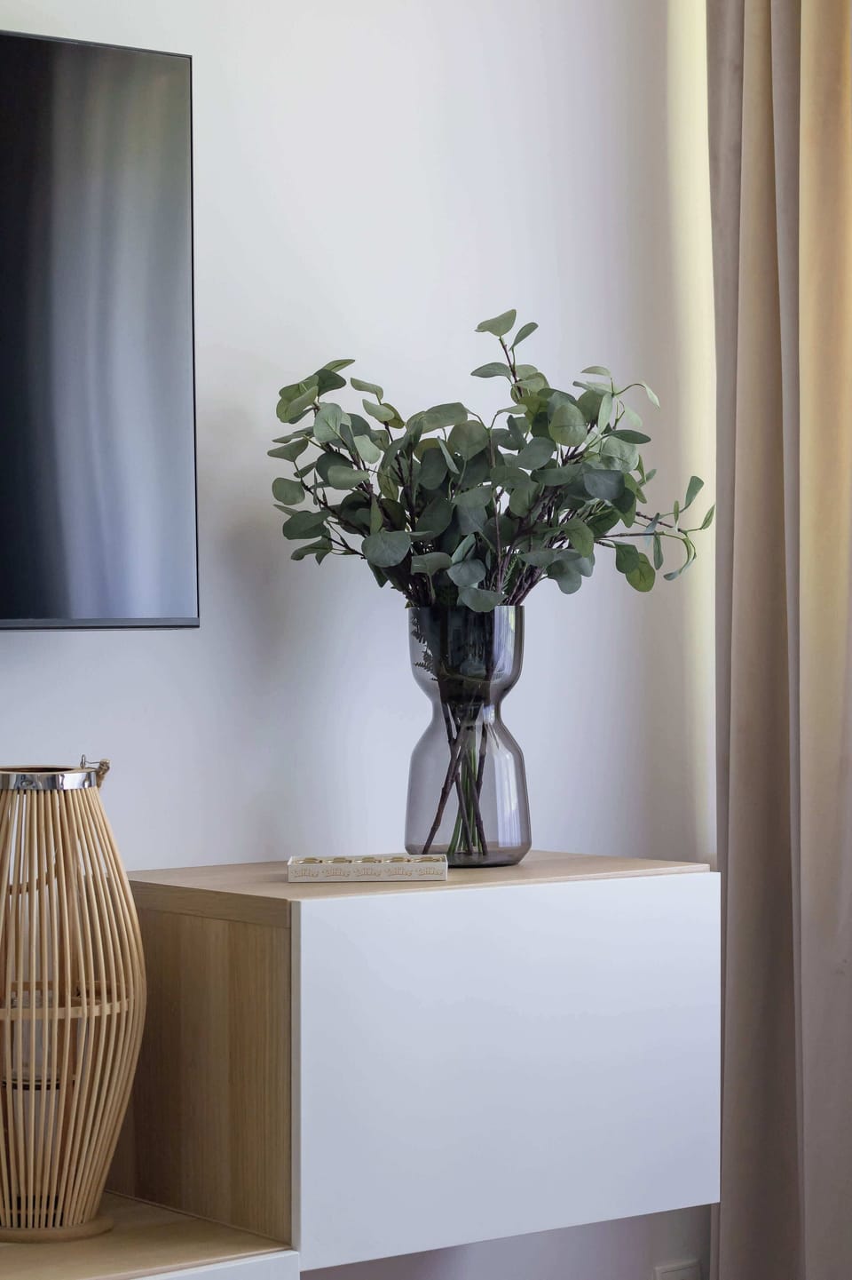 A vase of flowers on the cabinet under the TV.