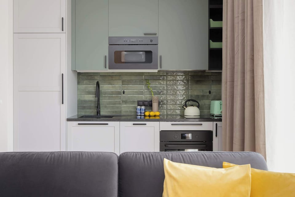 A compact, stylish kitchen with green-tiled backsplash and built-in appliances.