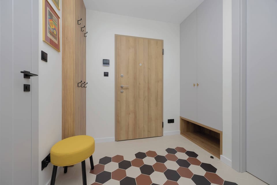 The hallway and entrance area with a yellow stool and stylish tiles.