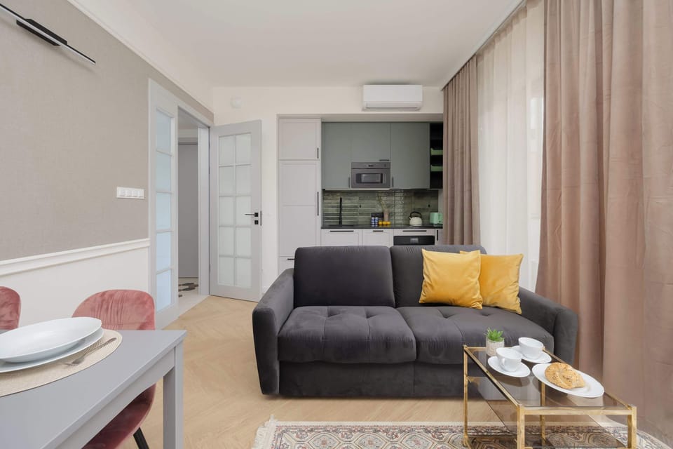 A cosy living room with a grey sofa, yellow cushions and a table for four.