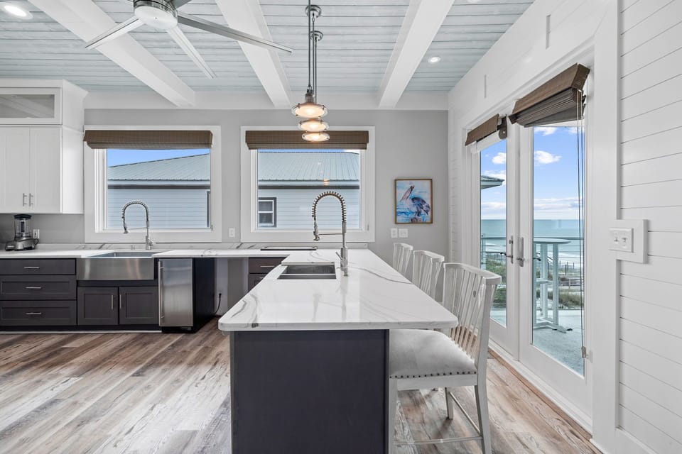 Your gourmet kitchen awaits with marble countertops, stainless appliances, and stunning ocean views through coastal windows.