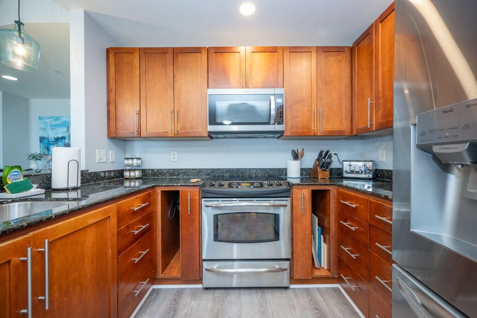 Bright, fully equipped kitchen featuring warm wood cabinetry, stainless steel appliances, granite countertops, and ample storage, perfect for preparing meals and gathering with family and friends.