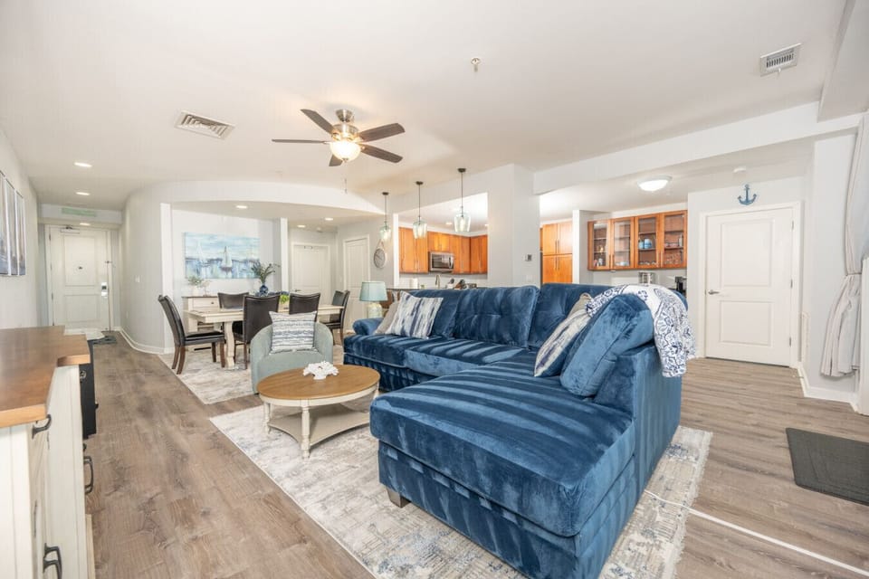Spacious open-concept living area with a plush sectional, coastal décor, and seamless flow into the dining space and kitchen.