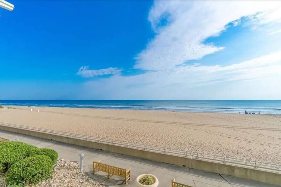 Step outside to a stunning oceanfront scene featuring a wide stretch of soft, golden sand and calm rolling waves.