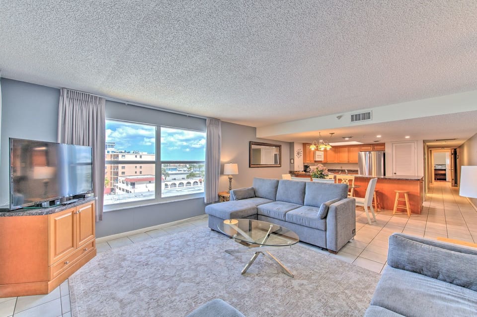 Unwind in your spacious living room with plush seating, city views, and open-concept design flowing into a modern kitchen.