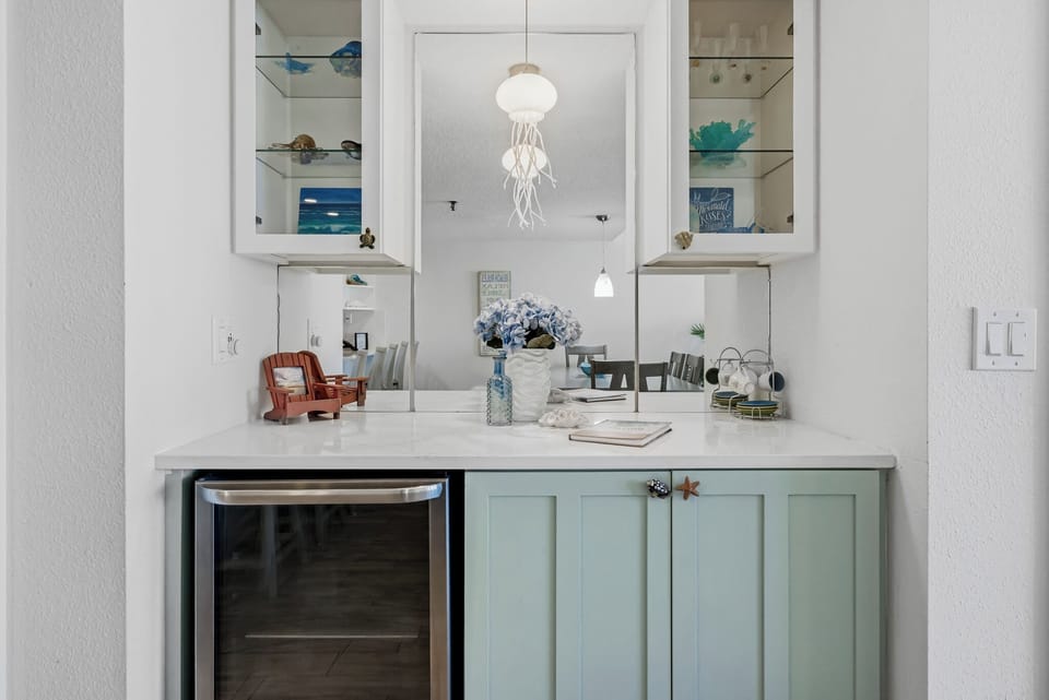 Your coastal-themed wet bar area features elegant marble countertops and charming sea-inspired décor, perfect for entertaining.