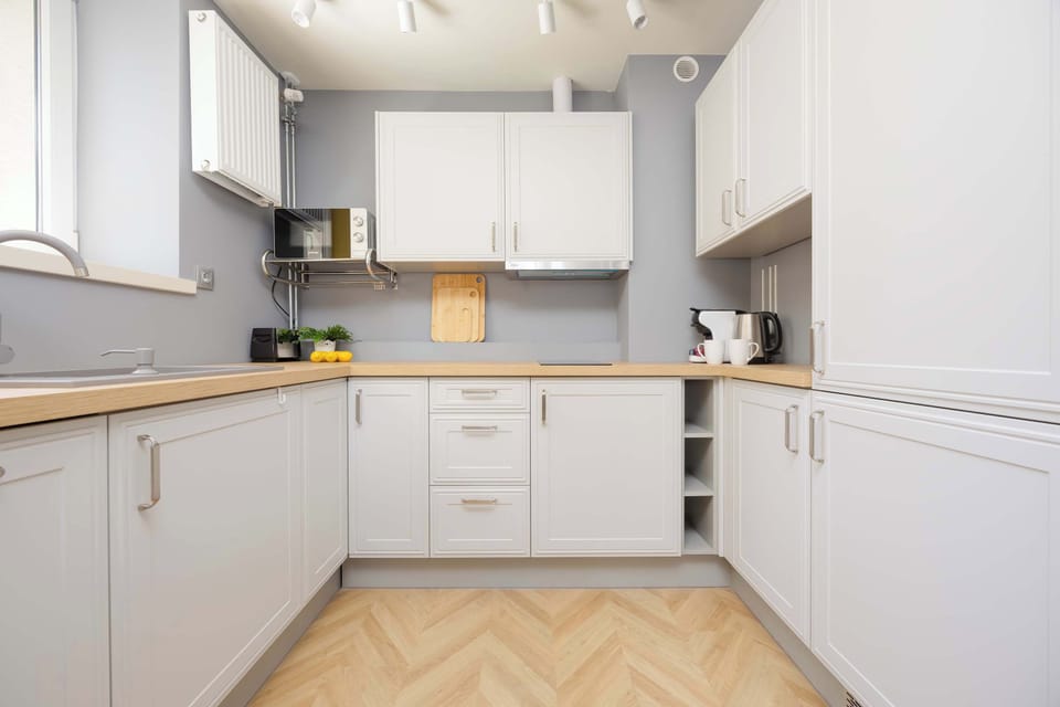 Modern white kitchen with built-in appliances and wooden countertop.