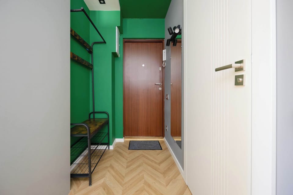 Green-painted hallway with a wooden door and a storage unit.