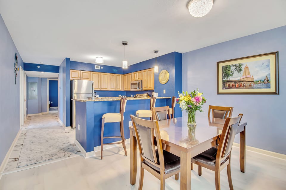 Gather around your elegant dining table in this vibrant blue kitchen, where fresh flowers and modern amenities create the perfect setting for memorable meals.