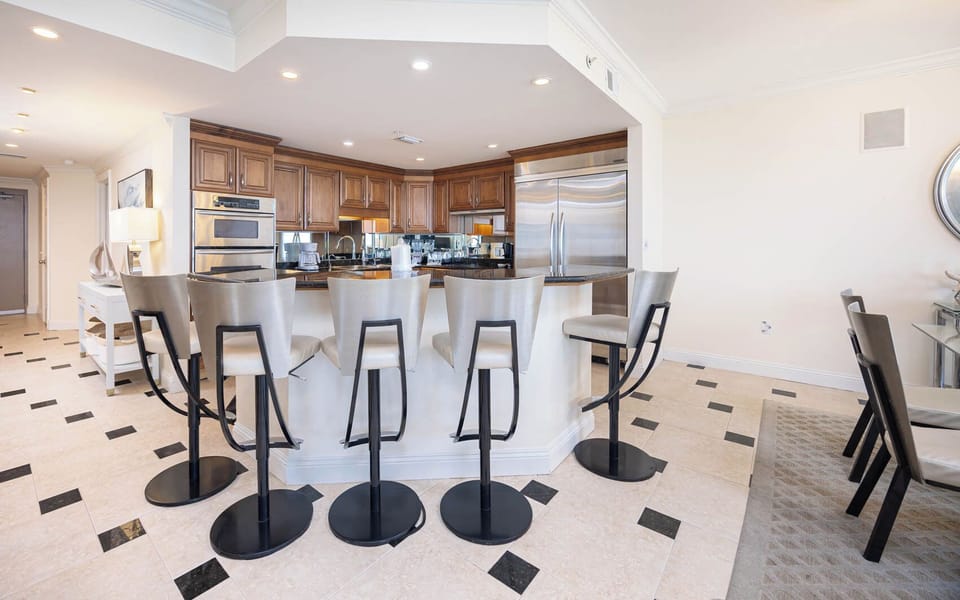 Enjoy casual meals or morning coffee at the sleek breakfast bar, surrounded by elegant cabinetry and an open kitchen layout