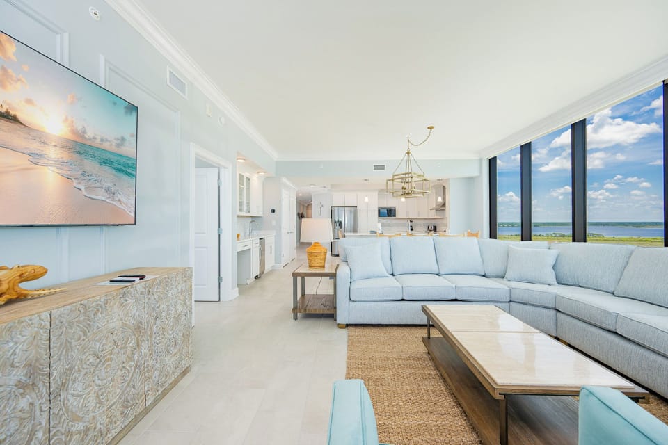 Relax in the spacious living area with a large sectional sofa, a flat-screen TV, and stunning beach views