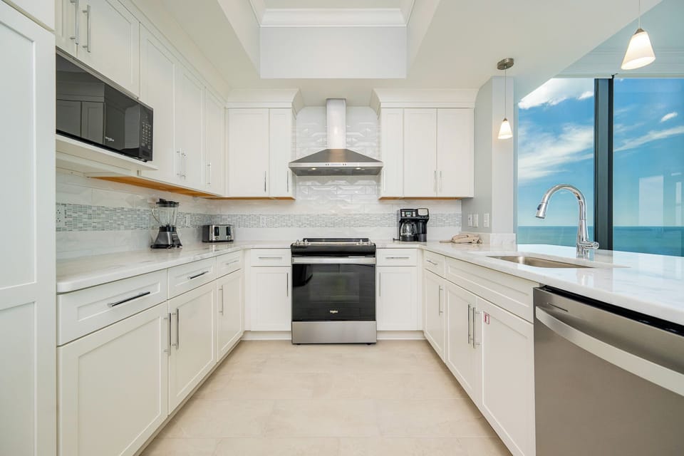 Prepare meals in this elegant kitchen featuring sleek cabinetry, modern appliances, and beautiful beach views