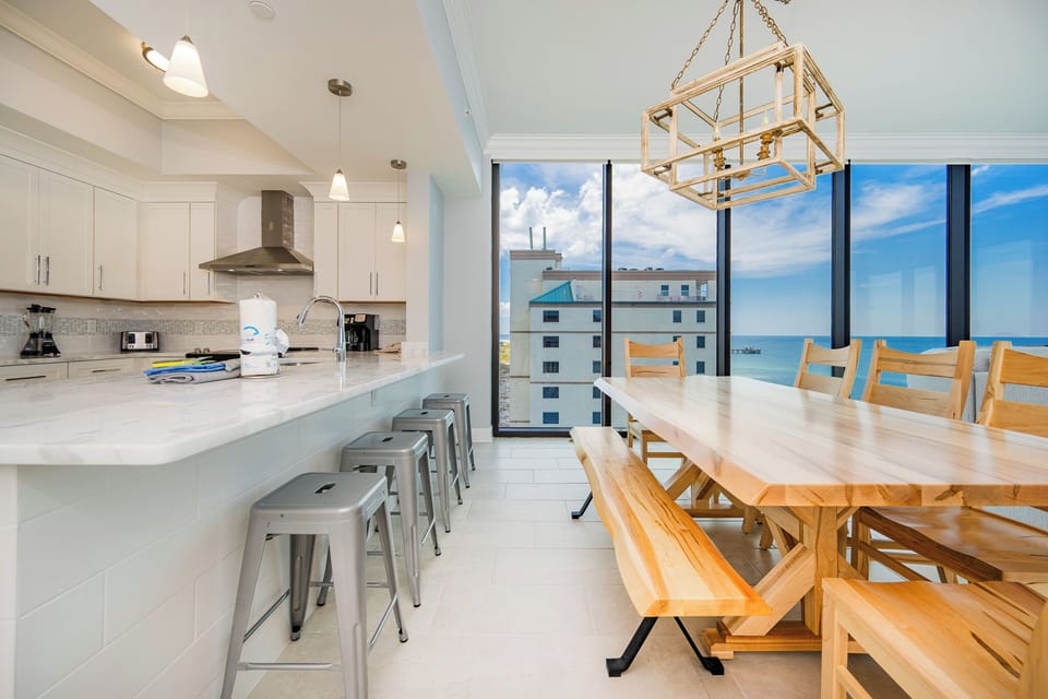 Gather around the large wooden dining table, enjoying the panoramic beach views