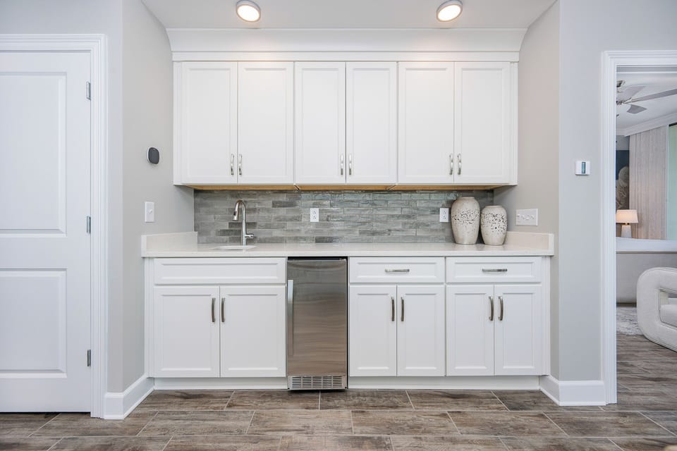 Prepare drinks with ease at the wet bat featuring sleek cabinetry and a small fridge