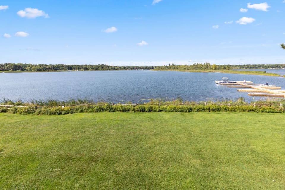 Expansive green lawn leading down to the calm lakeshore.