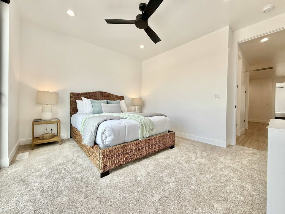 Cozy queen bedroom with soft carpet & fresh bedding — unwind & recharge in comfort during your stay