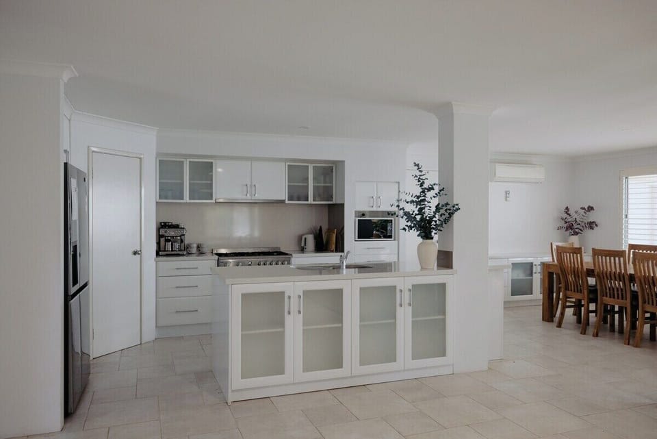 Sleek, open-plan kitchen featuring a large gas stove, microwave, full fridge, and seamless flow to the dining area with seating for 8.