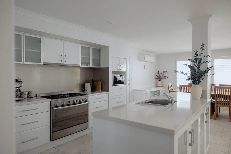 Bright and fully equipped kitchen with stainless steel appliances, spacious island bench, and coffee machine—perfect for home-cooked meals and morning brews.