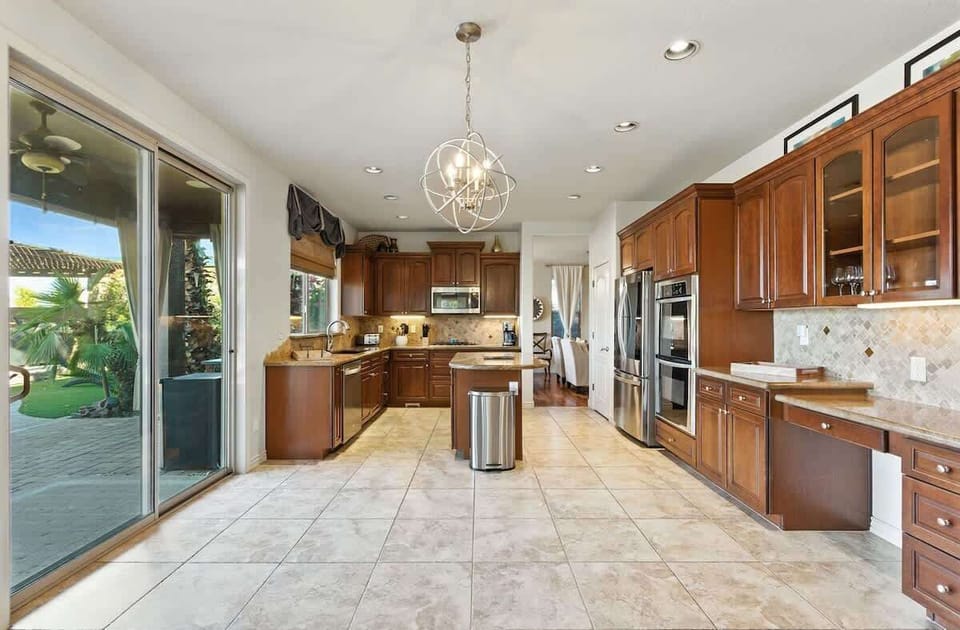 The fully equipped modern kitchen is stocked with all culinary essentials, stainless-steel appliances, a kitchen island, and private access to the backyard ranch retreat. (1st Floor)