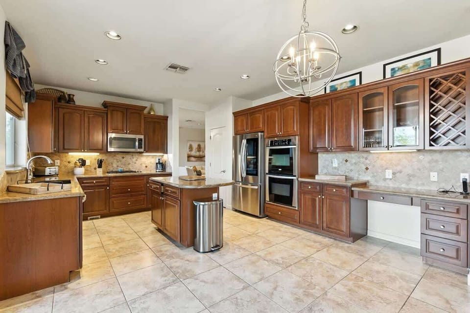 The fully equipped modern kitchen is stocked with all culinary essentials, stainless-steel appliances, a kitchen island, and private access to the backyard ranch retreat. (1st Floor)