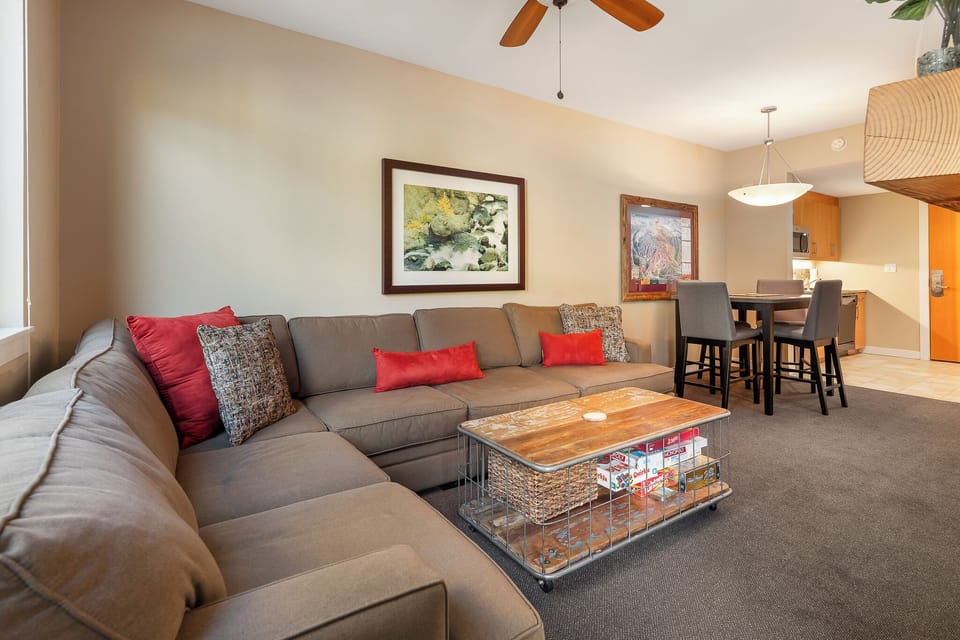 - Combined living and dining space with plush sectional and wood dining table - Seating for meals, board games, and late night chats all in one cozy area - Ceiling fans, art accents, and soft lighting create a comfortable atmosphere