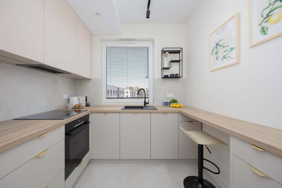 A compact kitchen with beige cabinetry, a black induction hob, and light countertops.