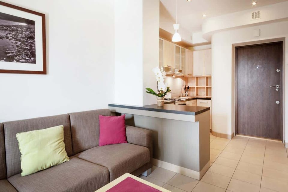 This image shows a small living room area with a gray couch adorned with colorful cushions. A piece of wall art hangs above, adding a pop of color and personality to the space.