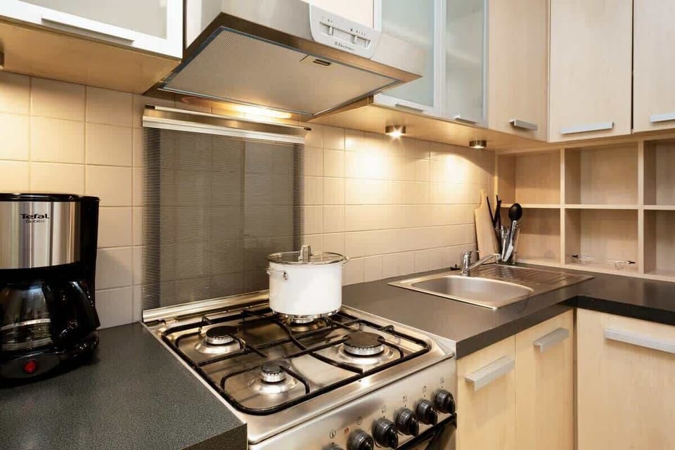 A close-up of a modern kitchenette with a stovetop, sink, and cabinets. The area is compact but well-organized, ideal for quick meal preparations.
