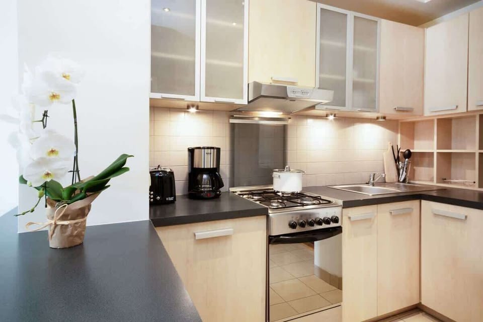 A sleek, modern kitchen with stainless steel appliances and a large counter space. The design is minimalist, with ample lighting and functional layout for easy meal preparation.