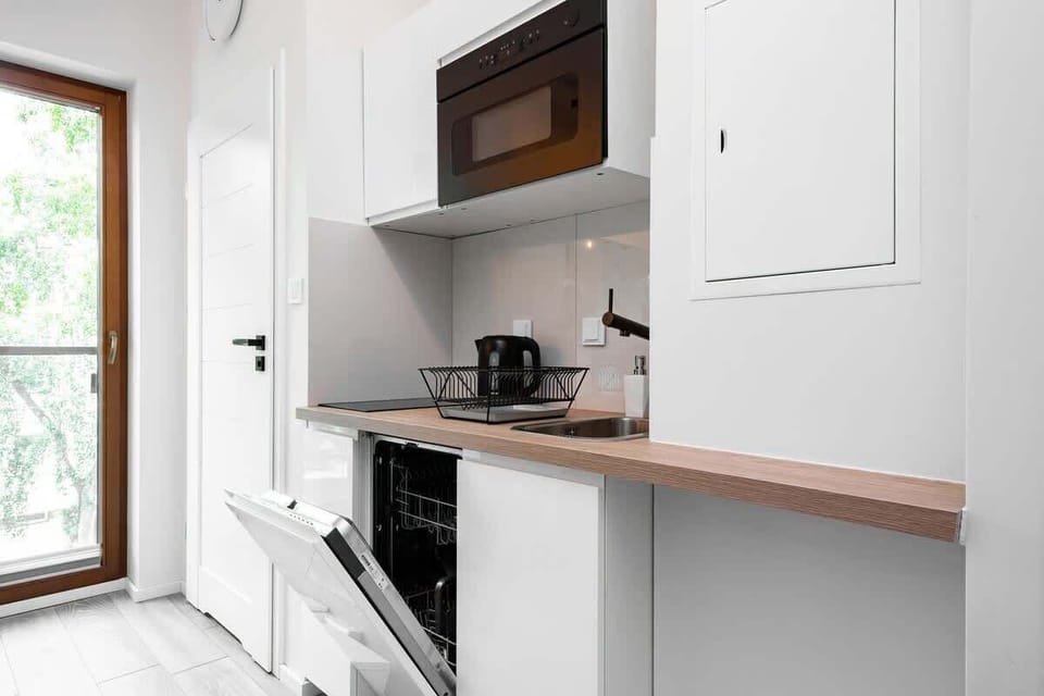 A kitchenette equipped with essential appliances and white cabinets, offering a convenient space for meal prep.