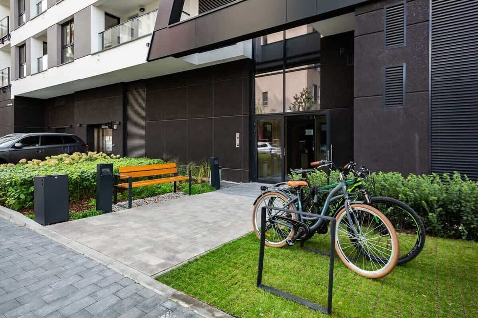 An exterior view of a building with a green lawn, a bicycle, and a landscaped outdoor area.