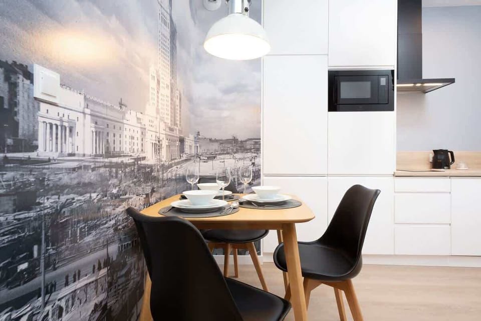 A dining area featuring a table with black chairs and a decorative mural depicting an urban cityscape.
