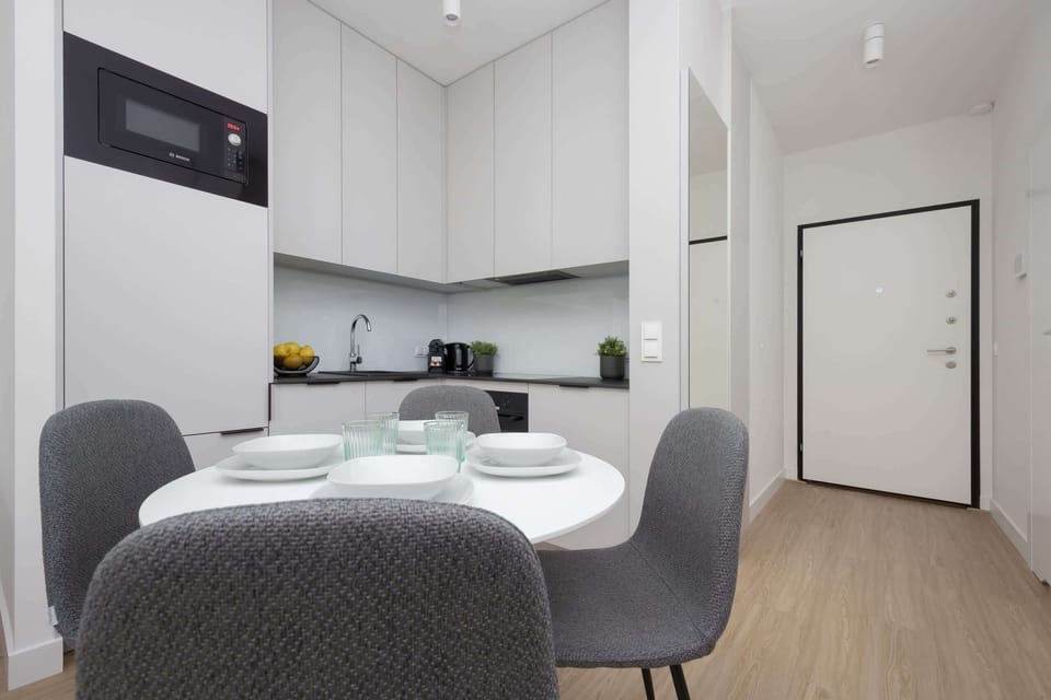 A contemporary kitchenette with built-in cabinets, a compact layout, and dining chairs arranged around a table.