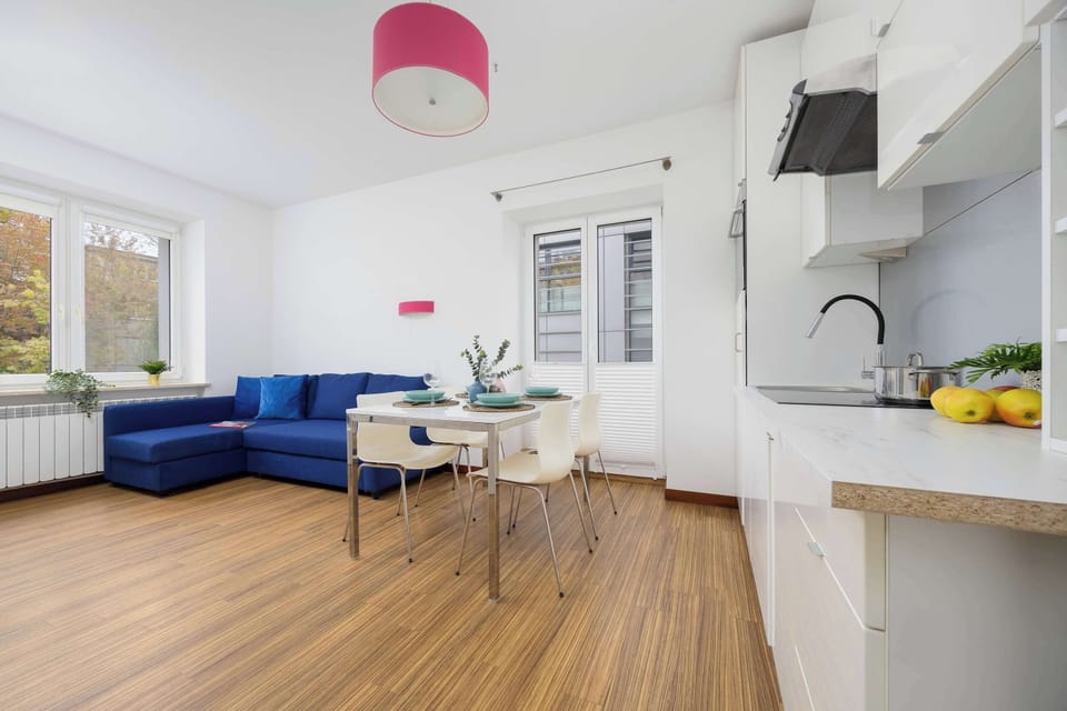A cozy living area with a blue sofa, connected seamlessly to a white kitchenette. The open-plan design offers a modern and airy feel.