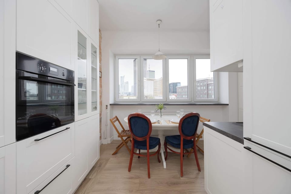 A small dining area inside a white kitchen, featuring a sleek modern design and plenty of daylight. Great for casual meals or working from home.