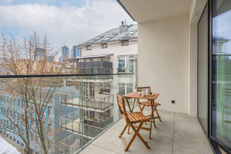 A cozy balcony with a small round table and two chairs, overlooking a scenic city view. The perfect spot to enjoy fresh air and relaxation.