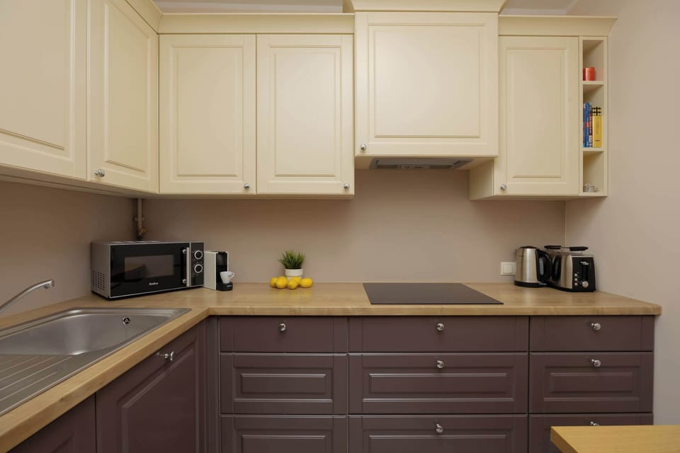 A modern kitchenette with cream and dark brown cabinets, equipped with essential appliances.