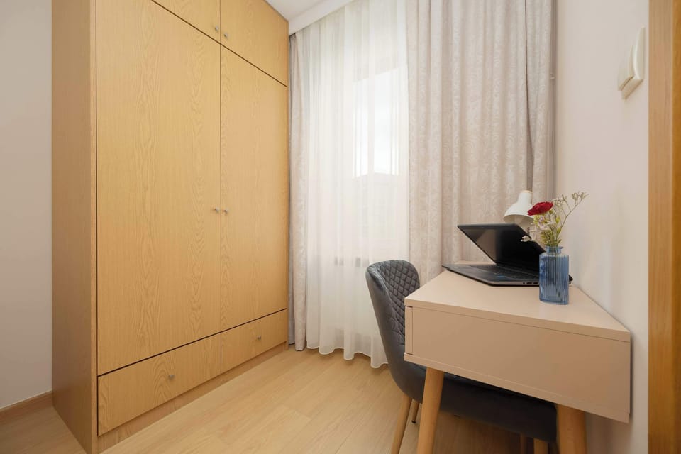 A small desk and wardrobe located near a window, ideal for working from home.