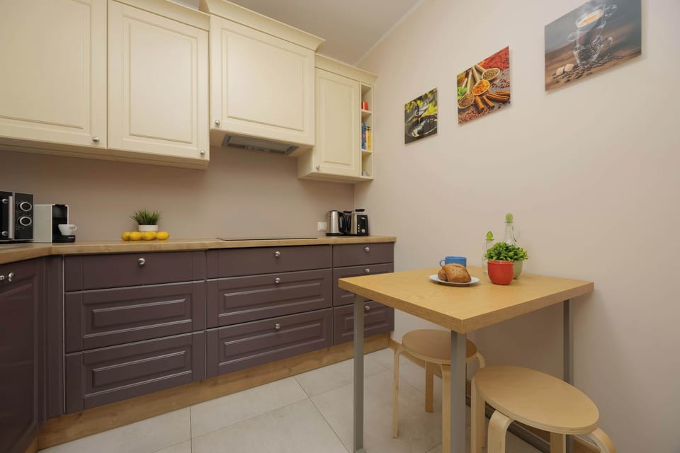 A modern kitchenette with cream and dark brown cabinets, equipped with essential appliances.