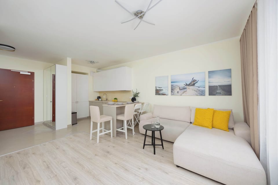 Living room with a sofa bed, TV, kitchenette and dining area.