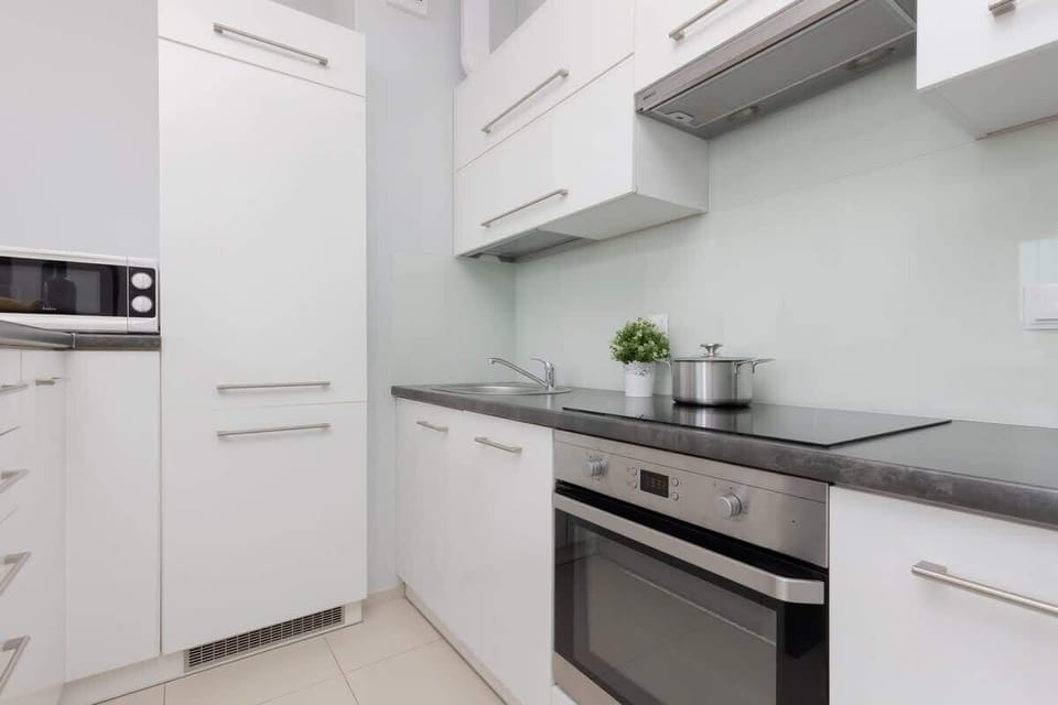 Compact white kitchenette with built-in appliances and clean finish.